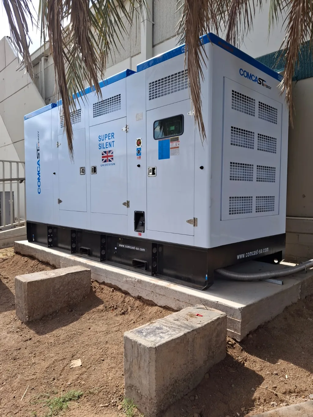 Planta eléctrica Comcast Energy de 400 kW instalada sobre base de concreto bajo una palmera